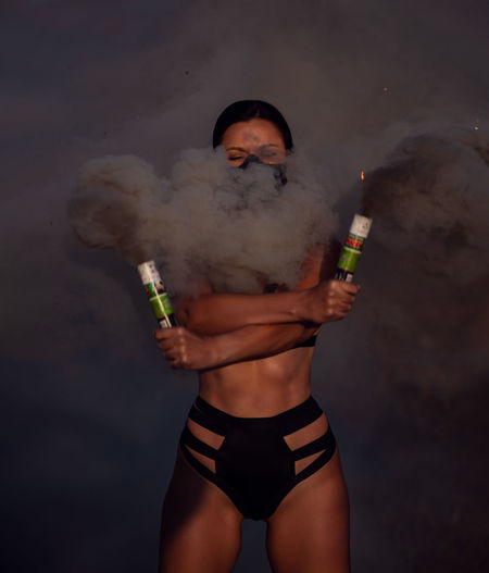 Woman in lingerie holding distress flare outdoors