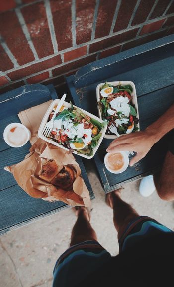 Low section of man standing by food while friend holding glass