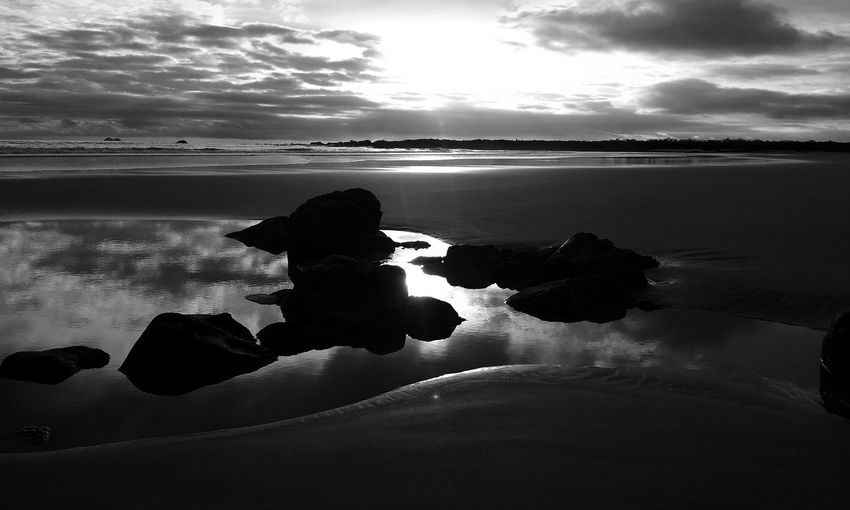 Silhouette rocks on beach against sky during sunset