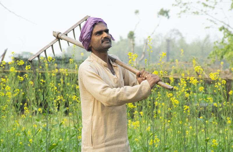 Farmer standing in field holding spade on his shoulder