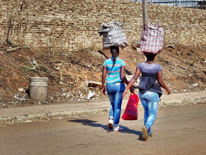 Rear view of women carrying bags on head while walking on street