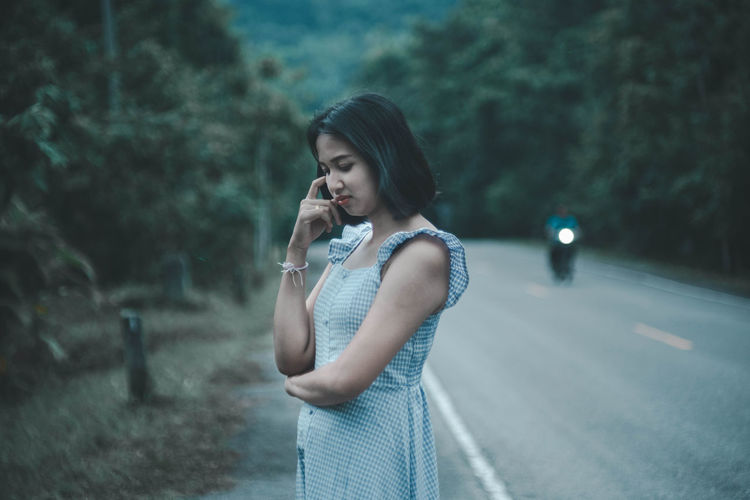 Woman standing on road against trees