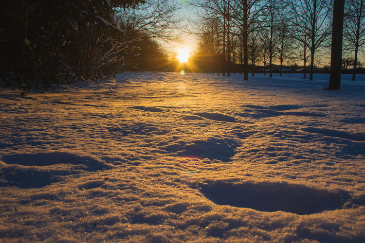 Scenic view of snow covered field during sunset