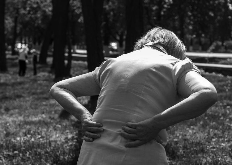 Rear view of woman with backache standing at park