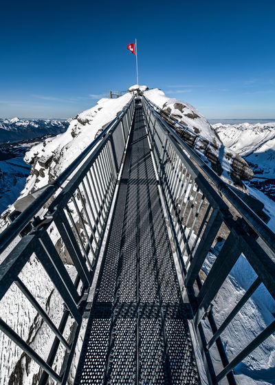 Low angle view of suspension bridge on snowcapped mountain against sky