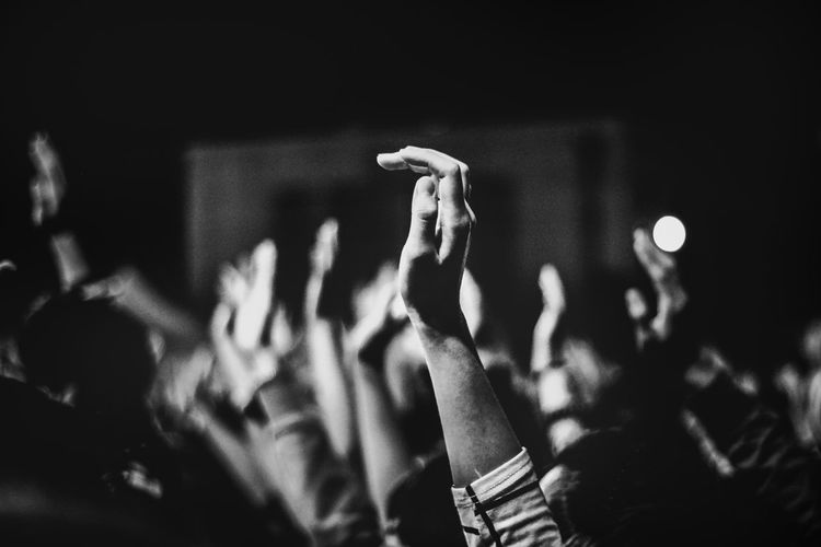 Cropped image of people with hands raised in music concert