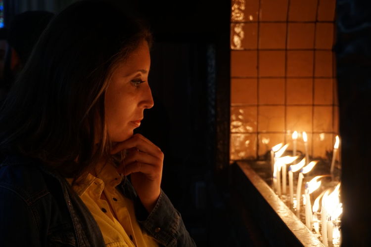 Woman looking at lit candles in darkroom