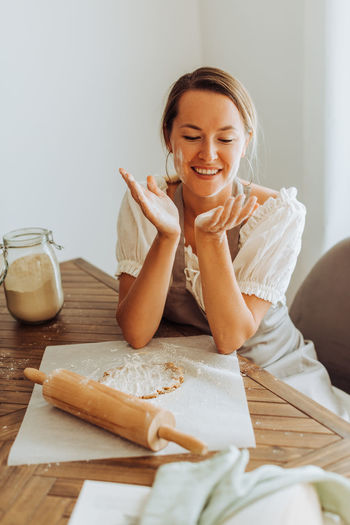 Woman sitting at kitchen table preparing dough for cookies