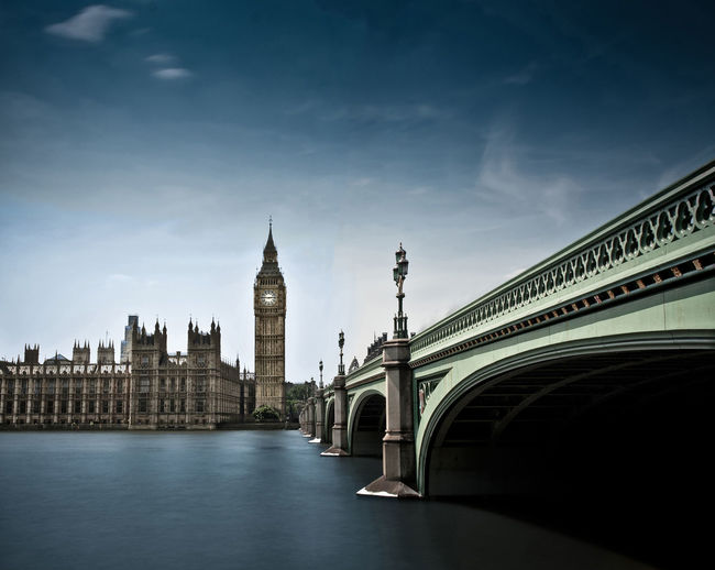 Westminster bridge over river leading towards big ben against sky in city