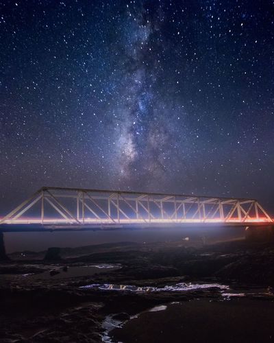 Illuminated bridge against sky at night