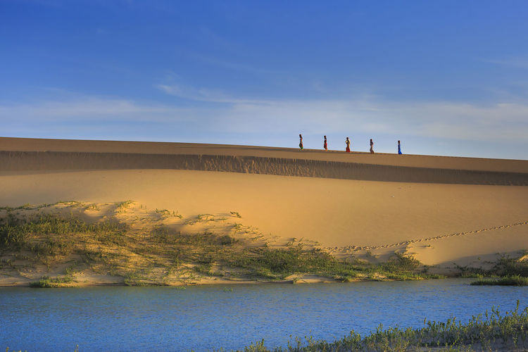  view of women carrying water on sand dune