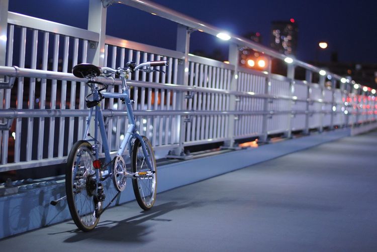 Bicycle parked on bridge in city at night