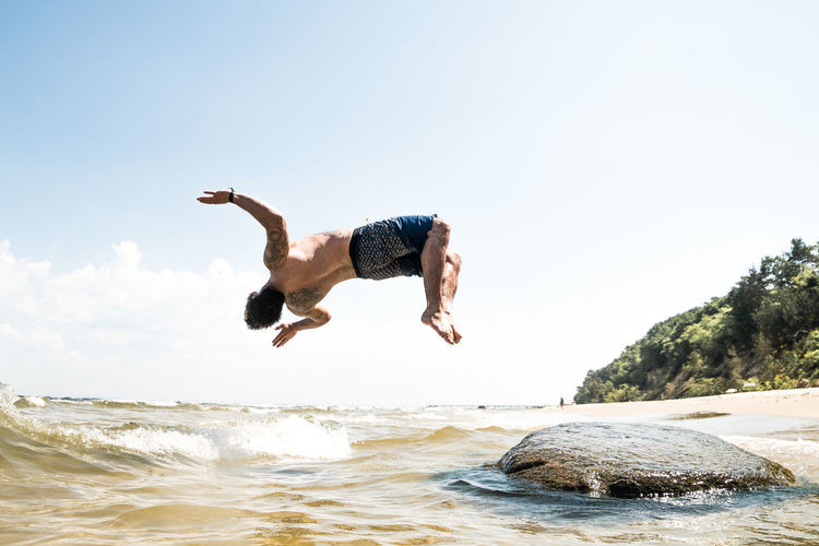 Full length of man diving in sea against sky