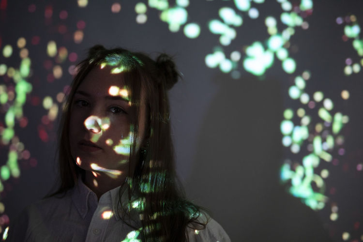 Portrait of young woman in illuminated lighting equipment