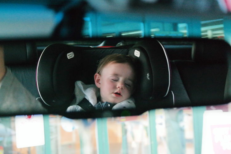 Cute toddler sleeping seen through rear view mirror of car