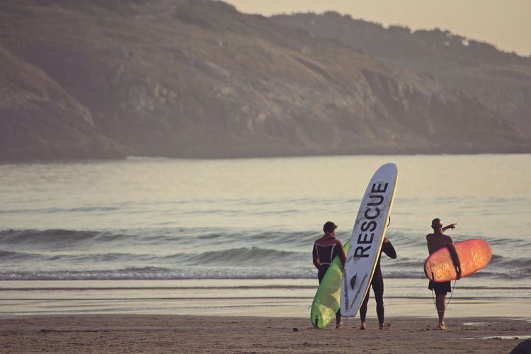 Rear view of people with surfboards at beach