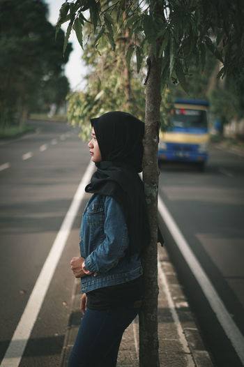 Side view of man standing on road in city