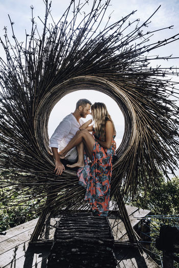 Side view of romantic couple sitting on circular sticks