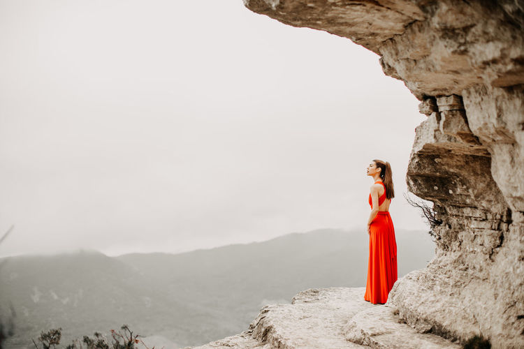 Woman standing on rock against clear sky