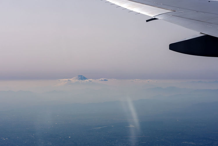 Airplane flying over fuji mountain against sky