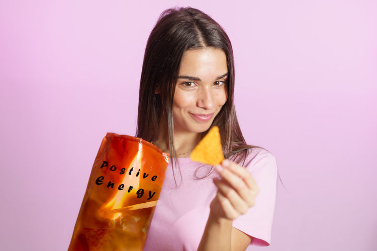 Portrait of young woman holding gift against white background