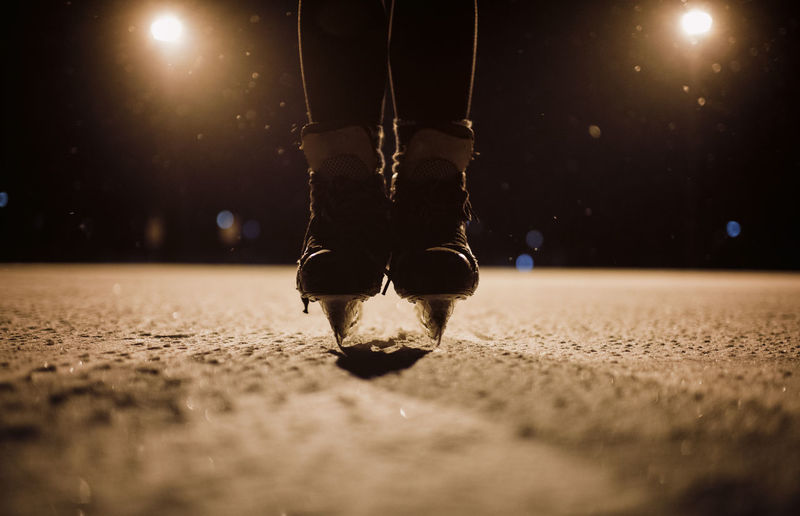 Low section of girl roller skating on street at night