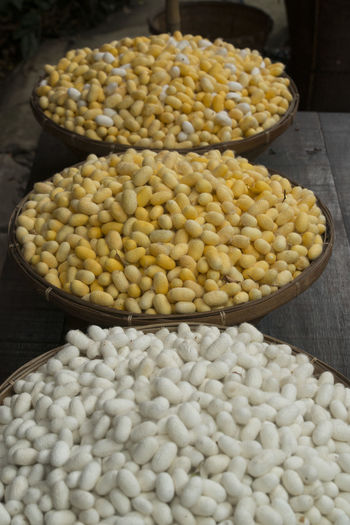 High angle view of white and yellow silk cocoons in wicker baskets