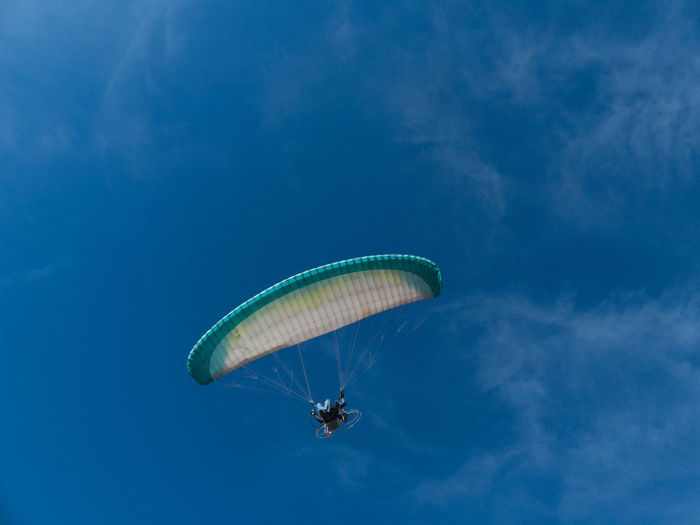 Low angle view of man paragliding against blue sky