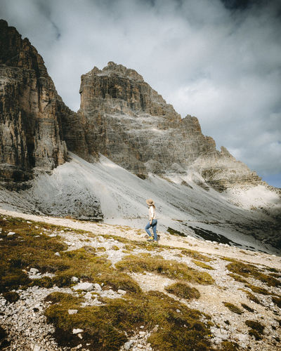 Rear view of woman walking on mountain against sky tre cime 