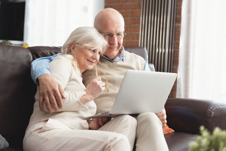 Man and woman using mobile phone while sitting on sofa