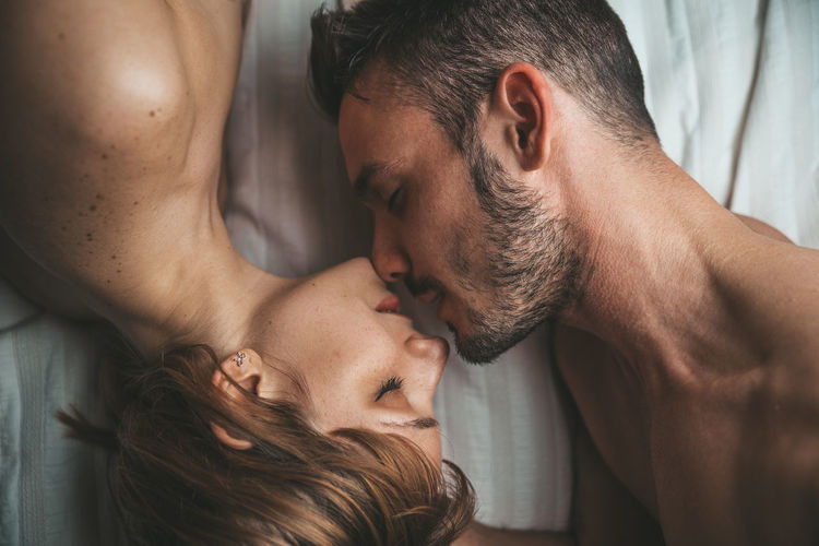 Directly above shot of shirtless couple on bed at home