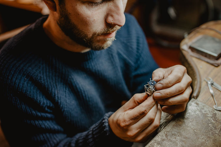 Jeweler holding unfinished ring in dirty hands and checking quality in workshop