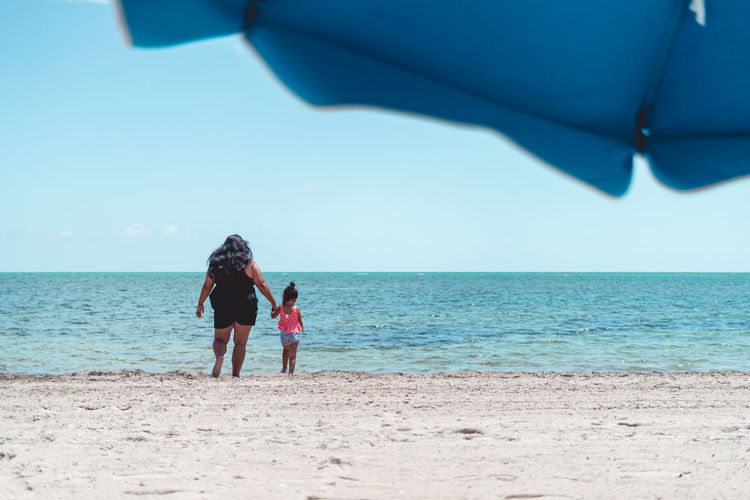 Rear view of woman standing at beach