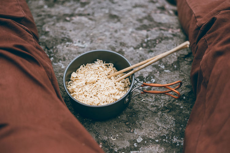 Midsection of person sitting by noodles in bowl