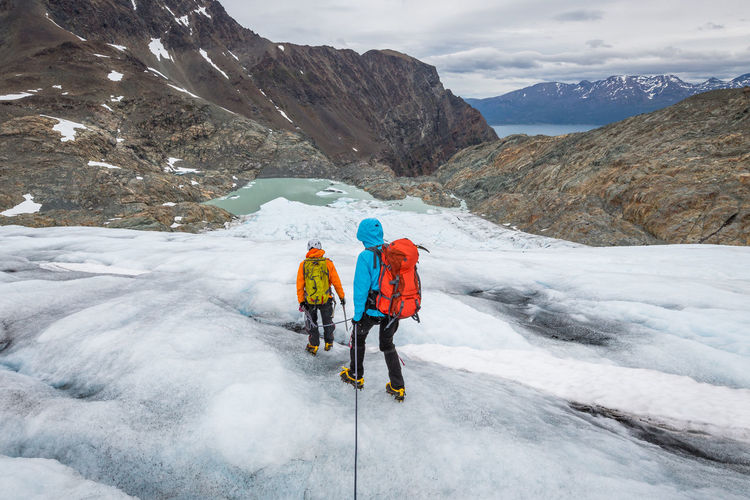 Rear view of hikers moving downhill on glacier
