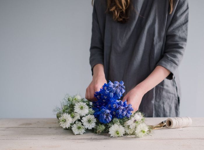 Close-up of hand holding bouquet against blue wall