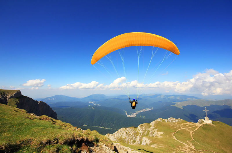One courageous person paragliding over mountains
