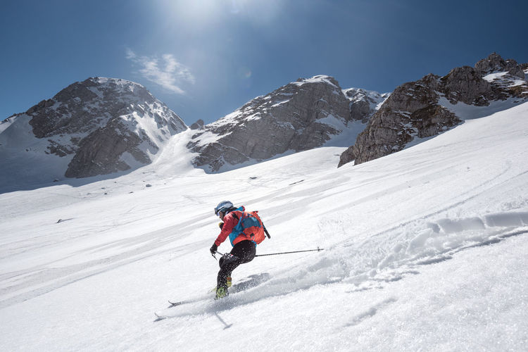 Man skiing on snow covered land against mountains and sky