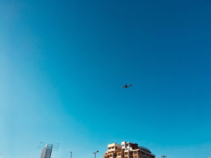 Low angle view of airplane flying against clear blue sky