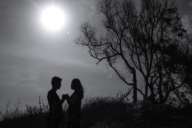 Silhouette couple kissing against sky