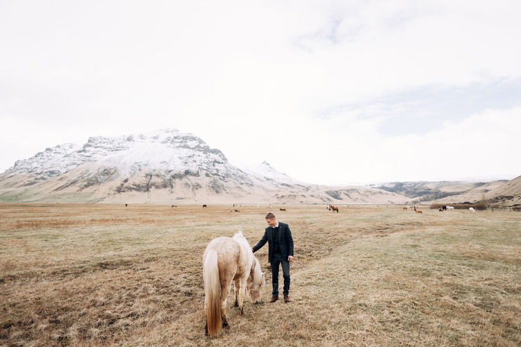 Full length of man patting horse