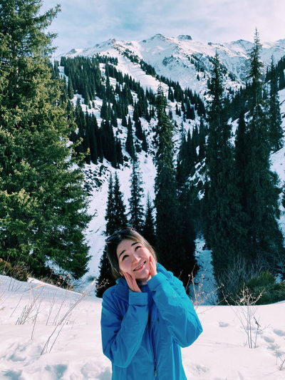 Portrait of smiling woman standing on snow covered mountain