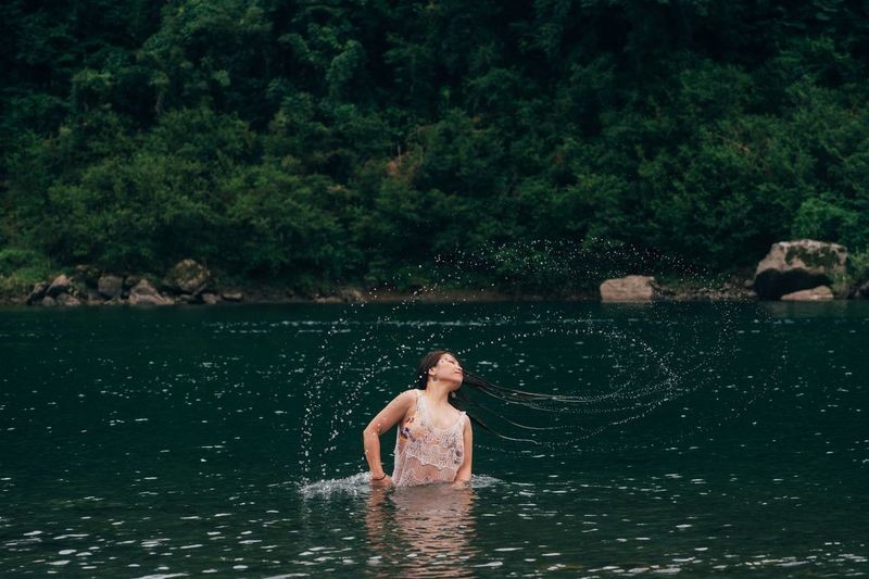 Woman tossing hair in lake 
