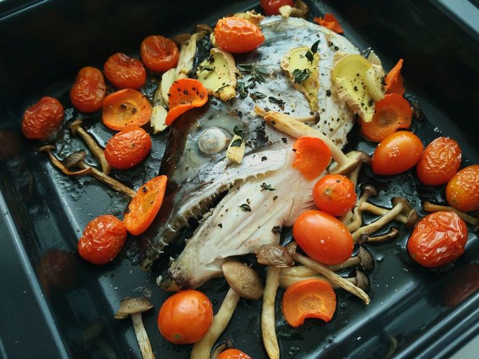 High angle view of baked fish and cherry tomatoes in tray