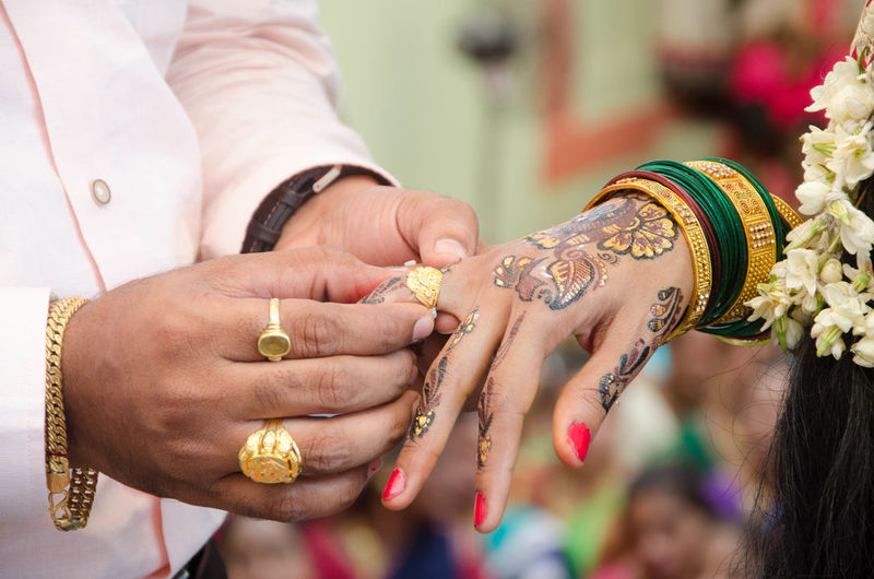Cropped image of bridegroom wearing ring to bride during wedding ceremony