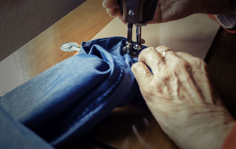 Cropped hands of woman sewing denim on machine