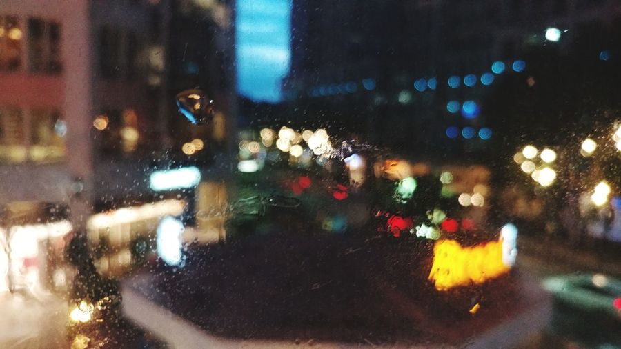 Defocused image of illuminated city seen through glass window