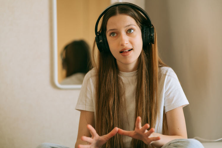 Beautiful generation z girl in headphones, listens to audio lessons, repeats