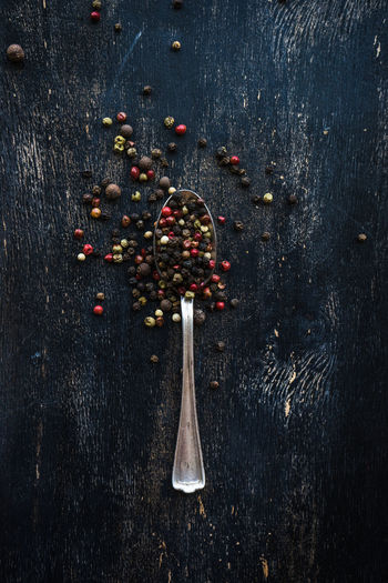 High angle view of peppercorns and spoon on table