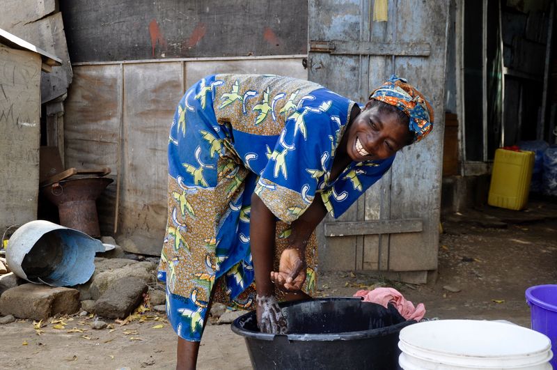 Cheerful woman washing clothes against house